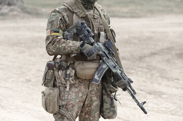 Soldier with machine gun and flag of Mozambique on military uniform. Collage.