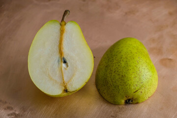 Two halves of ripe green pear on a copper surface.