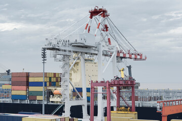 Large harbor crane loading containers on a large cargo vessel