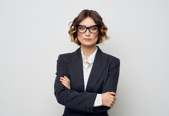 A business woman in glasses and in a suit on a light background crossed her arms over her chest