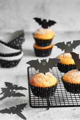 Halloween pumpkin muffins in black capsules decorated with cardboard bats. Festive Halloween...