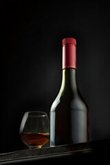 Bottle and glass of brandy on a wooden background.