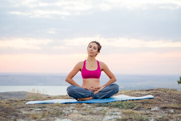 Fototapeta na wymiar young pregnant woman does yoga outdoors. Yoga at sunset