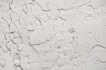 Cracked and grainy white stucco wall texture, macro shot. Old wall background.
