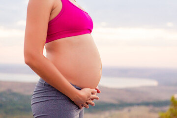 young pregnant woman does yoga outdoors. Yoga at sunset