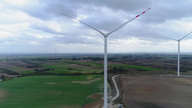 Line Of White Windmills Stop Spinning In A Wind Farm On A Cloudy Day In Kwidzyn, Poland - Wide Shot (Drone)