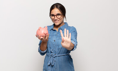 young hispanic woman smiling and looking friendly, showing number four or fourth with hand forward,...