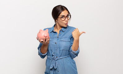 young hispanic woman looking astonished in disbelief, pointing at object on the side and saying...