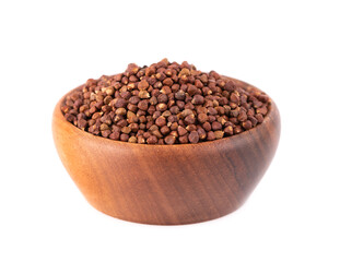 Guinea pepper grains in wooden bowl, isolated on white background. Melegeta, alligator pepper or mahlab. Grains of paradise.