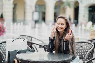 Fototapeta premium shopping in the outlet store online sale. holds a Bank card in his hands. economical woman European appearance ethnic designer freelancer drinks coffee to take away in a paper Cup in a cafe.