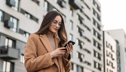 Portrait of stylish smiling business woman in fashionable clothes calling on mobile phone near office. Female business style.