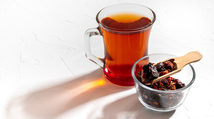 Rosehip tea in a clear glass mug and dried rosehips in a small cup. Copy space.