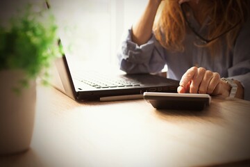 business woman hand with calculator and computer on desk