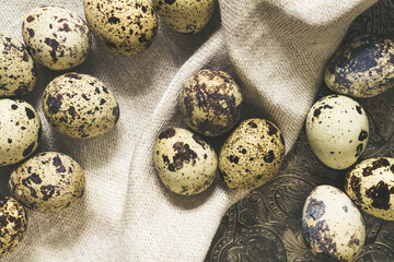 Obraz premium Several multi-colored quail eggs with a linen napkin on a dark background