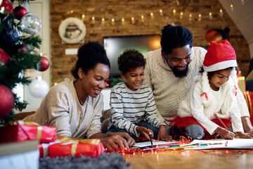 Fototapeta na wymiar Happy black family enjoying while coloring during Christmas day at home.