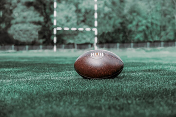American football, rugby ball on green grass field background. Vintage color filter