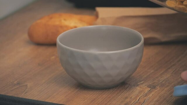4k slowmotion video of cropped view of male hand with a bowl of cornflakes.