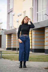 A beautiful girl with long hair in a black warm sweater. Young stylish woman in jeans culottes