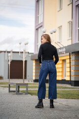 Fototapeta premium A beautiful girl with long hair in a black warm sweater. Young stylish woman in jeans culottes