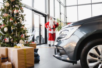 Santa Claus near a new car in a car dealership.