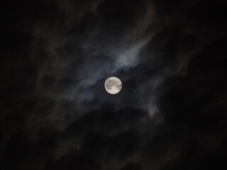 Naklejka na ściany i meble A huge moon in the clouds takes glory from a dim star.