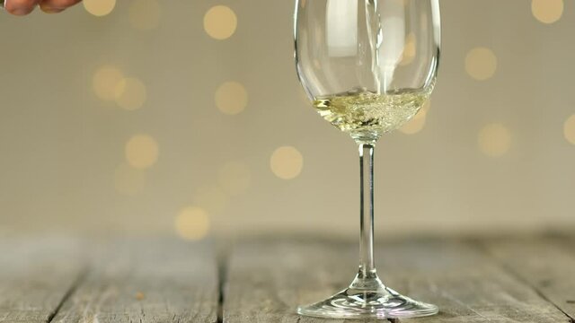 waiter pouring white wine in a glass on a wooden restaurant table