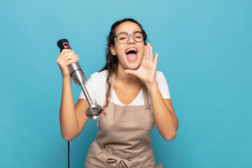 young hispanic woman feeling happy, excited and positive, giving a big shout out with hands next to mouth, calling out