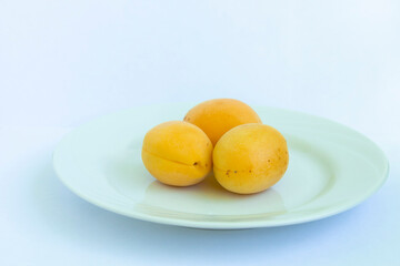 Naklejka na ściany i meble THREE FRUITS, peaches, ON A WHITE CERAMIC PLATE AND ON A WHITE BACKGROUND. healthy food concept