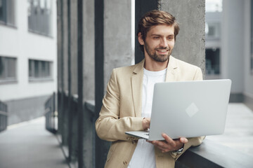 Happy man in suit working on portable laptop on fresh air
