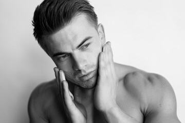 Muscular sexy model sports young man. Black and white portrait of beautiful smiling healthy guy applying foam for washing on his face. Facial skincare routine.