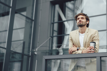 Naklejka na ściany i meble Relaxed businessman in earphones standing on balcony