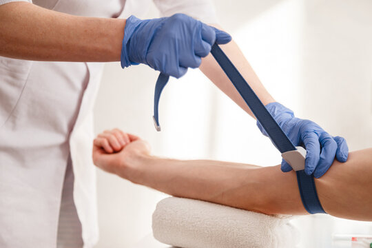 Nurse fastens the medical tourniquet on arm before taking blood test