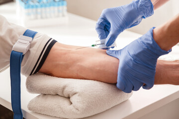 The nurse draws blood from a vein for test.