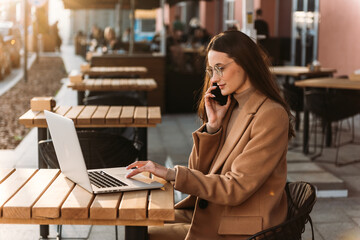 Beautiful business woman working on laptop outside her office, freelance concept. Young attractive business woman sitting on the stairs and using modern laptop.
