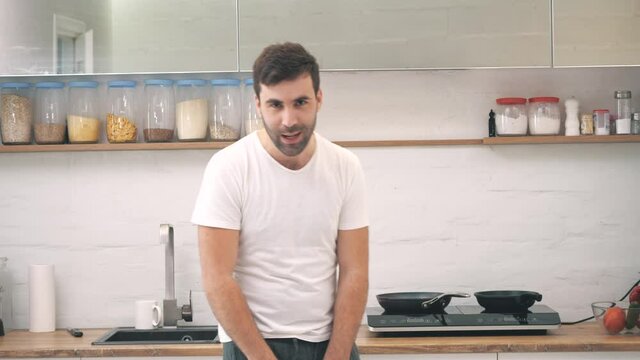 4k video of joyful man posing in the kitchen at home.