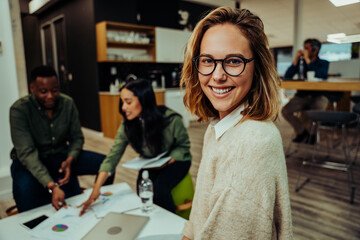 Close up portrait of beautiful smiling caucasian businesswoman sitting with friendly colleagues discussing work before meeting
