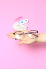 Glasses and contact lenses on a pink background. Vision correction. Glasses for sight. Glasses or contact lenses.