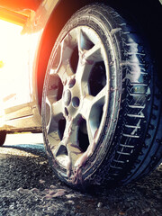 Close up of a car wheel during washing. Cleaning a car tire with  foamy cleanser. Profile view of a soapy wheelset before the rinse. Rinsing vehicle wheels with water, view from below.