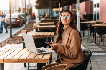 Beautiful business woman working on laptop outside her office, freelance concept. Young attractive business woman sitting on the stairs and using modern laptop.