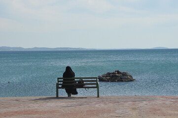 a woman with veiling watching the sea