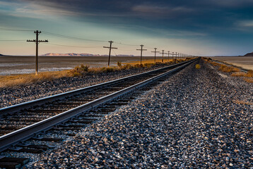Une belle image de paysage d& 39 une ancienne voie ferrée dans le désert avec une ligne télégraphique à côté et des montagnes en arrière-plan. Cette belle image a été prise lors d& 39 un coucher de soleil à l& 39 heure d& 39 or.