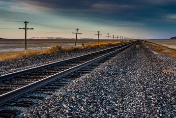 Papier peint photo autocollant rond Chemin de fer Une belle image de paysage d& 39 une ancienne voie ferrée dans le désert avec une ligne télégraphique à côté et des montagnes en arrière-plan. Cette belle image a été prise lors d& 39 un coucher de soleil à l& 39 heure d& 39 or.