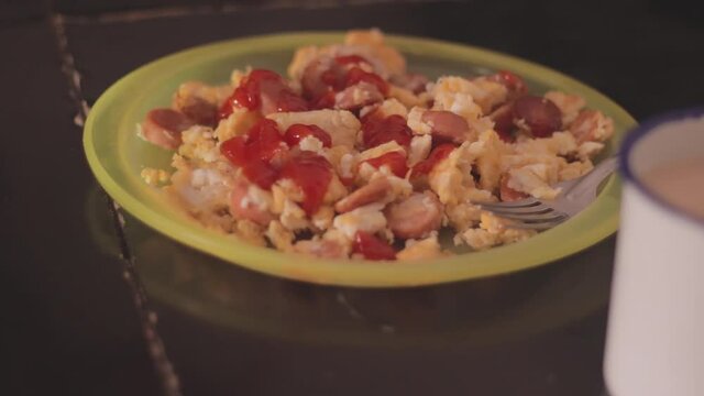 woman putting ketchup on her egg with sausage.