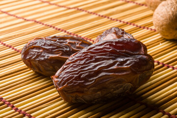 Big luxury dried date fruit on the bamboo mat, kurma ramadan kareem concept, close up.