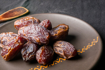 Big luxury dried date fruit in bowls on the dark surface, kurma ramadan kareem concept, close up.