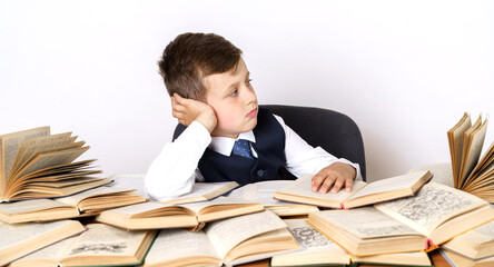 The student is doing his homework, he is tired looking around. There are many open books on the table.