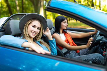 Two happy friends women in the cabriolet driving everywhere and looking for freedom and fun
