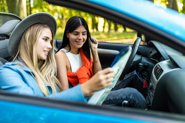 Two women reading a map in a convertible car