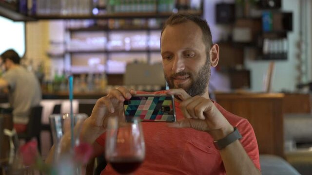 Young man taking smartphone selfie photo with wine in cafe