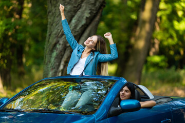 Freedom. Happy free woman in cabriolet cheering joyful with arms raised. Woman going on road trip travel on summer day